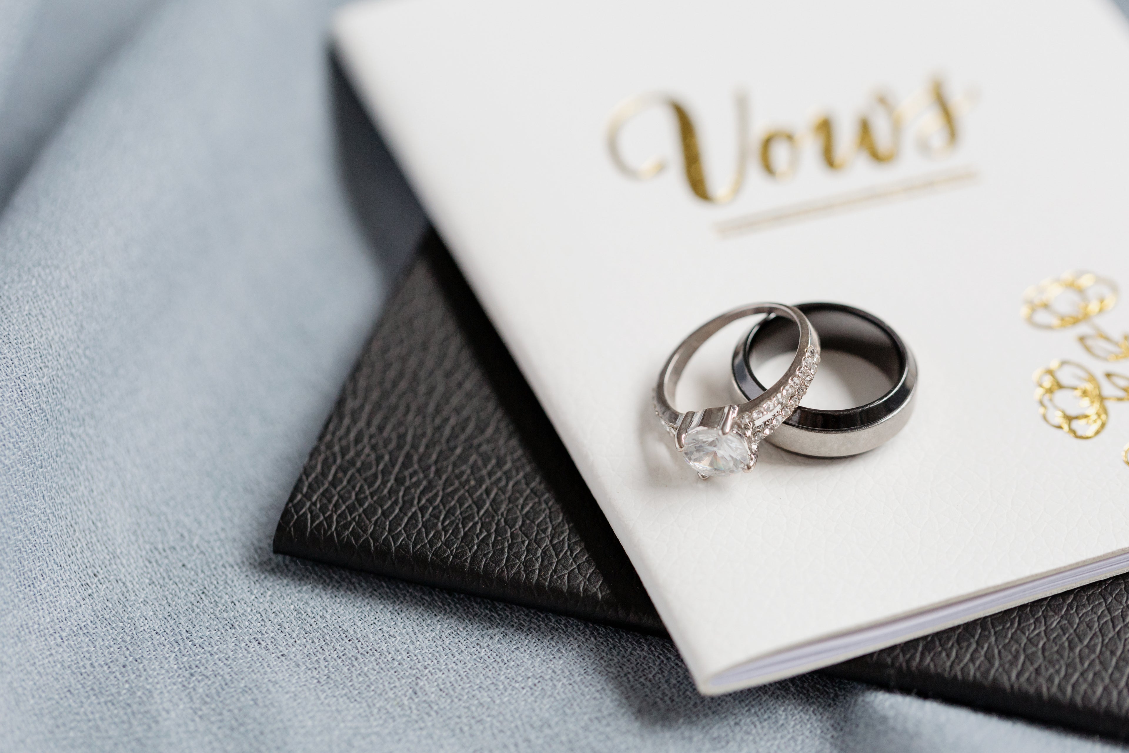 a set of wedding rings placed o the cover of white notebook labeled Vows
